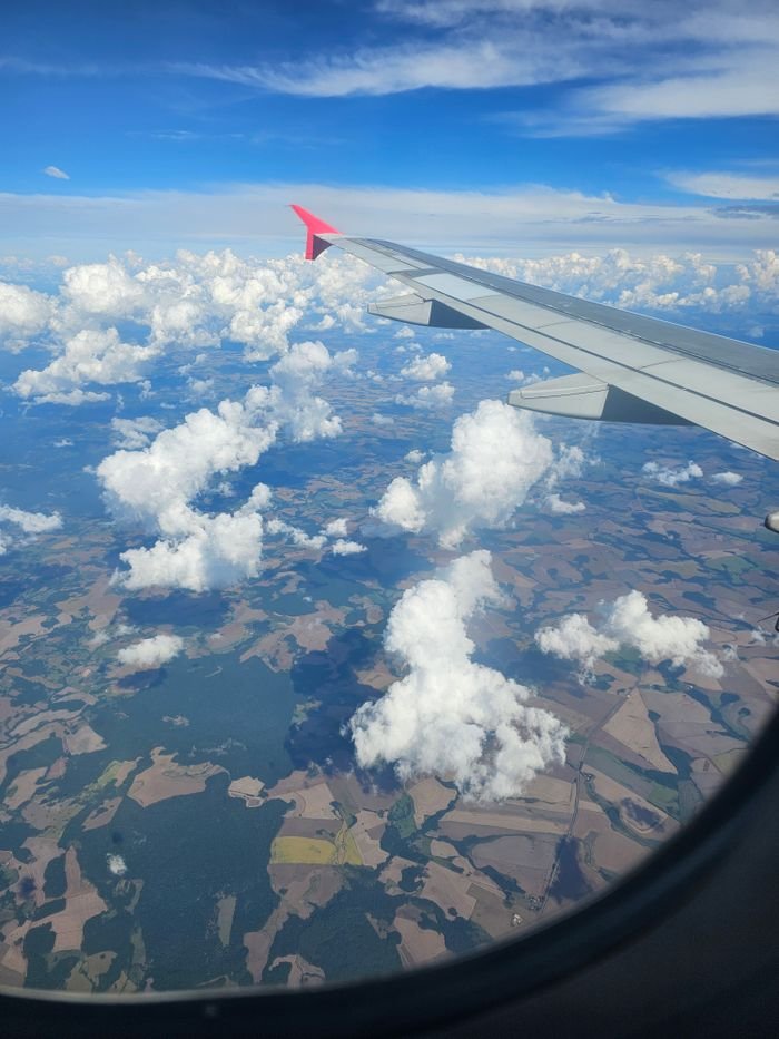Stunning aerial view from airplane over clouds and landscape, capturing the vast sky.