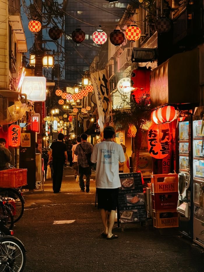 Bustling Tokyo street at night with traditional lanterns and pedestrians.