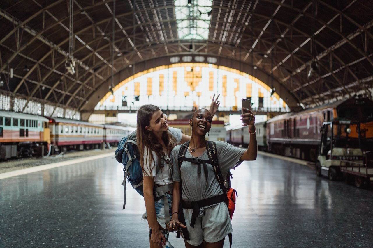 Two backpackers capturing their travel moments in a beautiful historic train station.